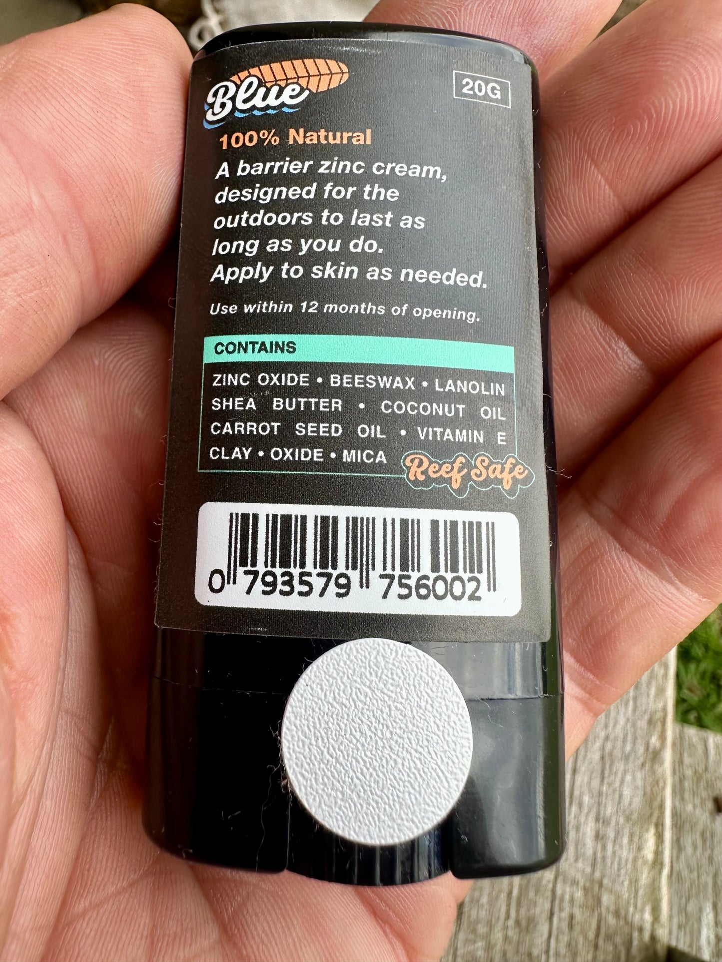 Hand holding a tube of Blue 100% Natural zinc cream with label details.